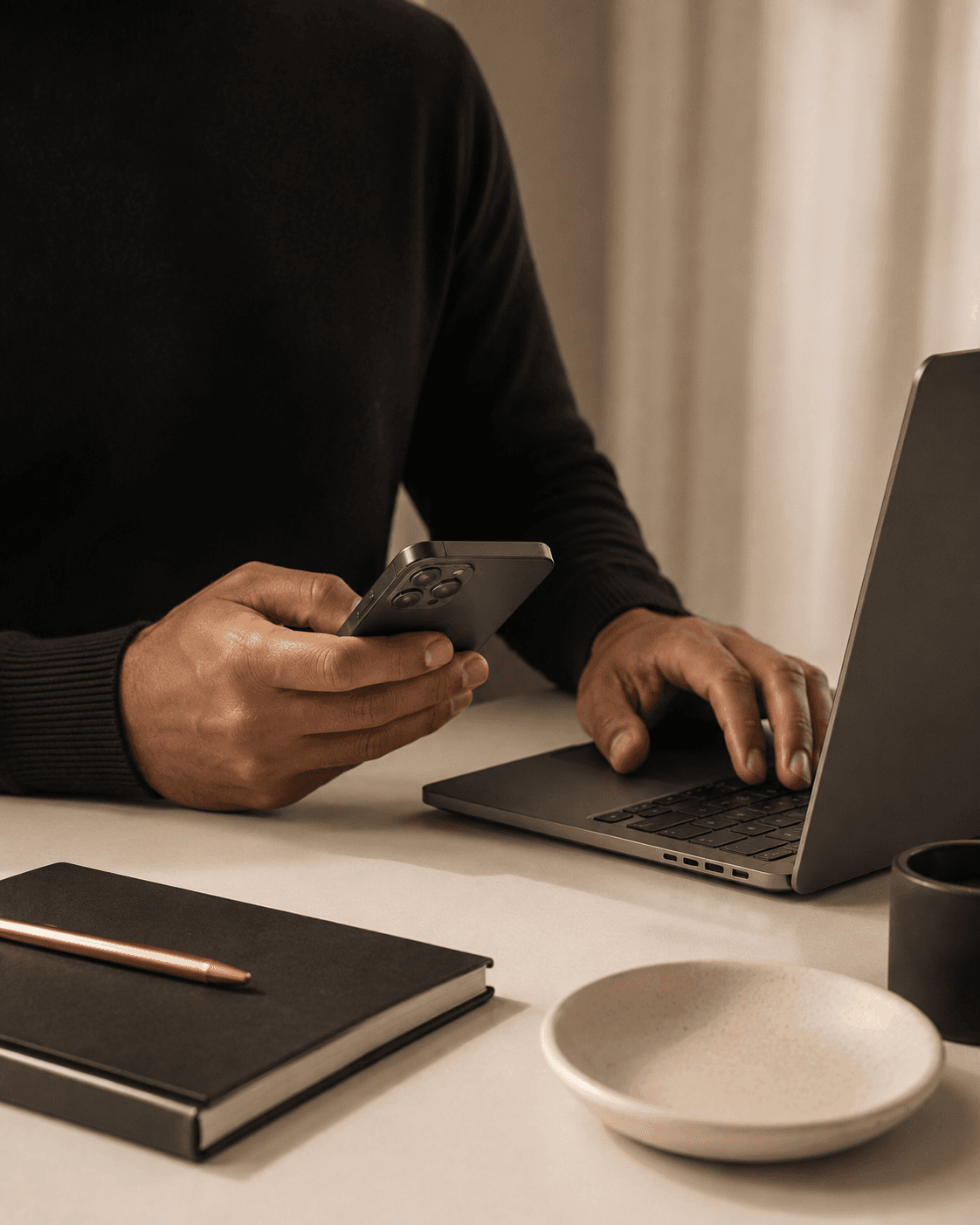 Hands holding a phone beside an open laptop