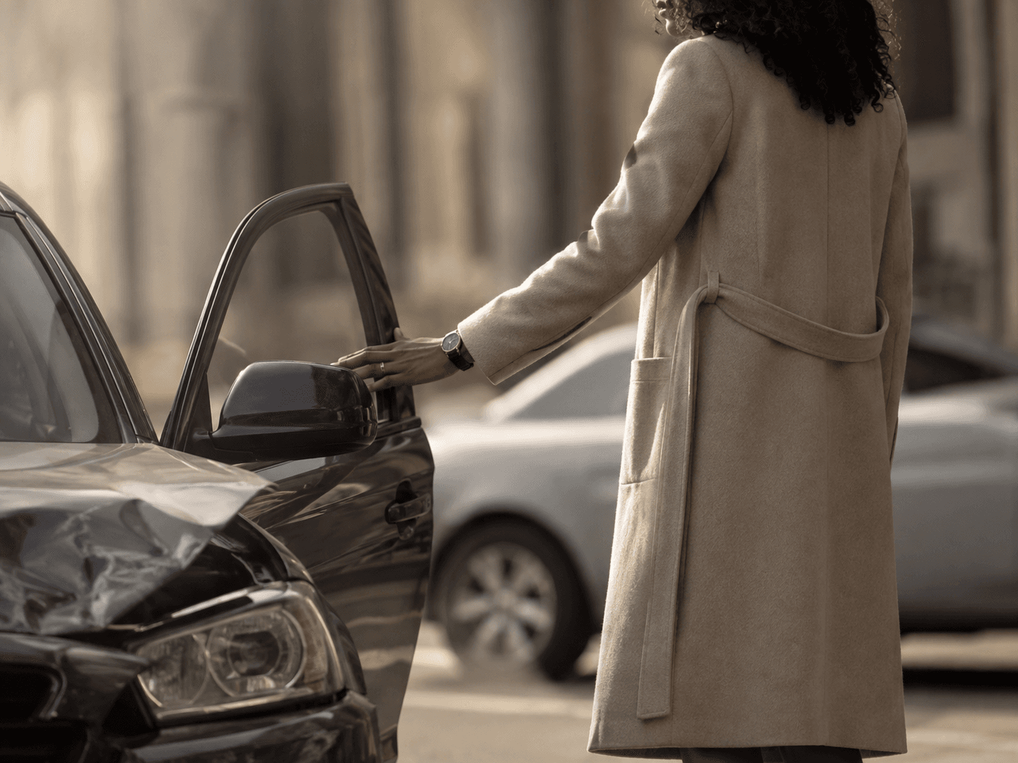 A woman opening the door of a damaged car